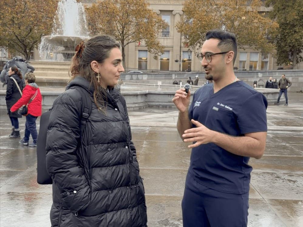 Dr Dev Gakhar in scrubs interviewing a member of the public in Trafalgar Square