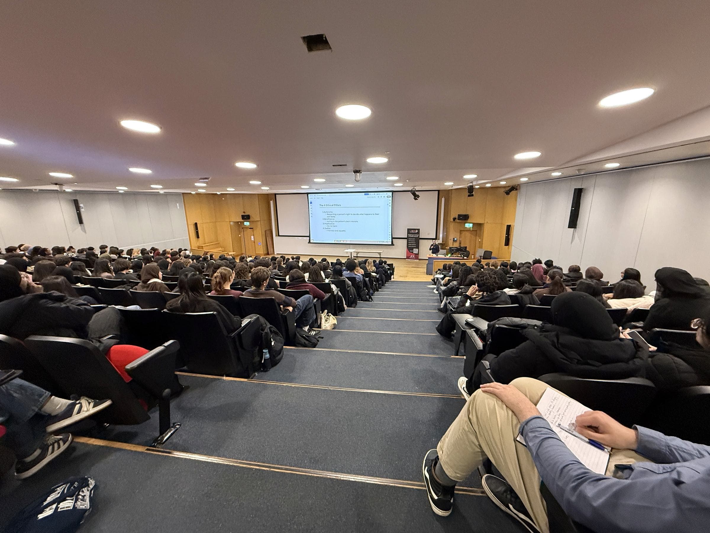 A full university lecture theatre, Dr Dev Gakhar presenting from the stage